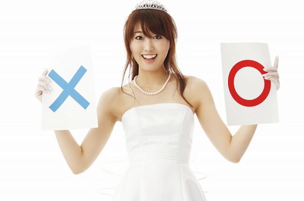 ウェディングドレスを着た女性がマルバツ札を持っている