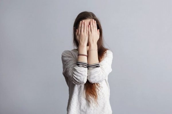 恥ずかしくて顔を隠す女性