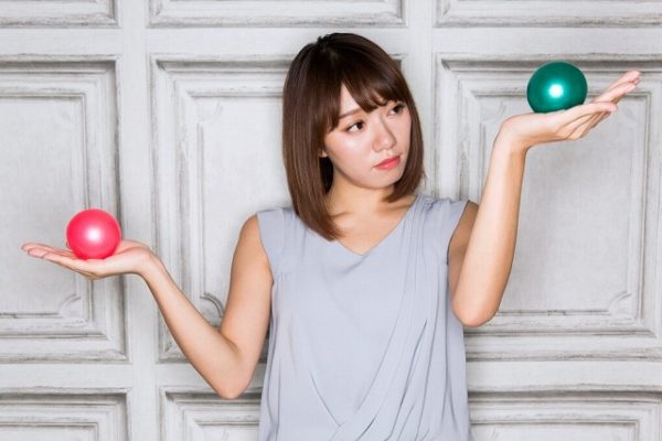 緑と赤のボールを比較する女性