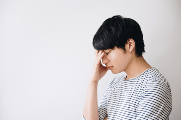 顔を覆って悩む男性