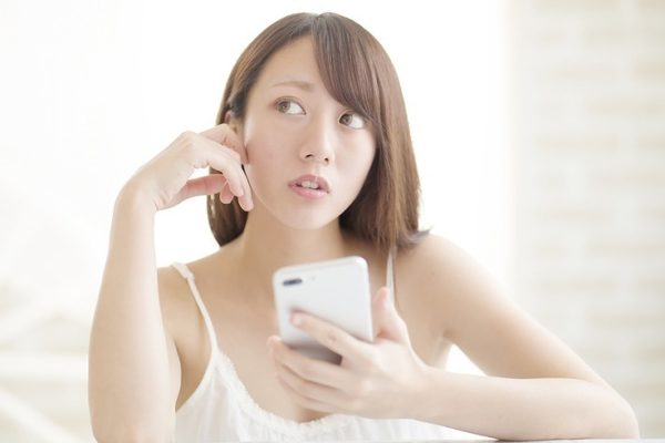 考えながらスマホを操作する女性