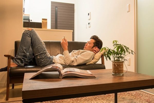 部屋のソファでくつろぐ男性
