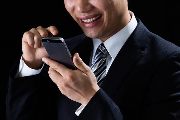スマホを操作して不敵な笑み浮かべる男性