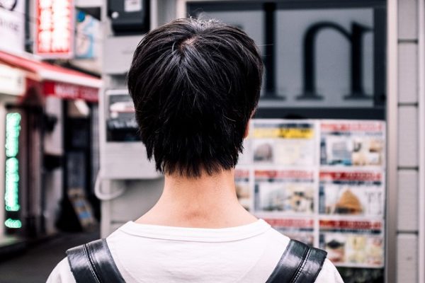 街にいる若い男性の後ろ姿