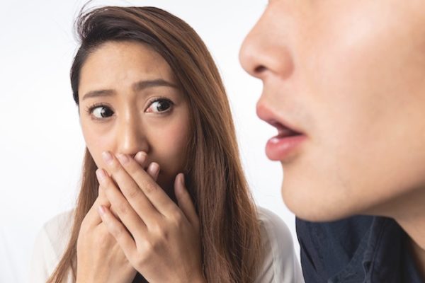 男性の口臭に口を塞ぐ女性