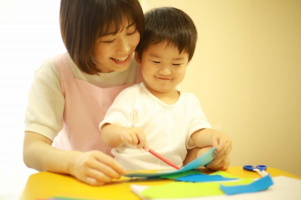子供のお絵かきを見る保育士